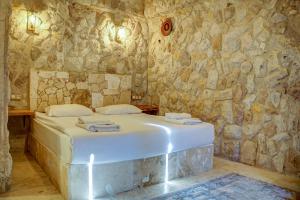 a bedroom with a bed in a stone wall at Ala Stone Hotel in Göreme