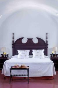 a bedroom with a large bed with white sheets and a table at Monasterio de San Francisco in Palma del Río