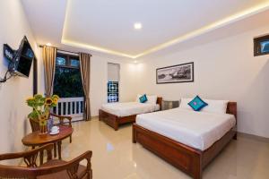 een hotelkamer met 2 bedden en een tafel bij Papaya Garden Homestay in Hội An