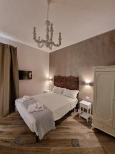 una camera da letto con un grande letto bianco e un lampadario a braccio di Real Giardinetto a Toledo a Napoli