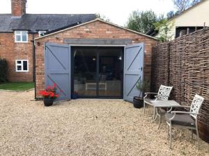 a large blue garage with two chairs in a yard at Bank Studio - luxury Cotswolds haven for two in Shipston-on-Stour