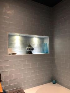 シップストン・オン・ストアにあるBank Studio - luxury Cotswolds haven for twoの白いタイル張りの壁のバスルーム(棚付)