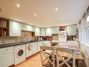 a kitchen with white cabinets and a table and chairs at 3 Dunrobin Street in Tain