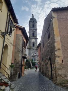 una persona caminando por una calle con una torre de reloj en A Casa di Zio, en Campagnano di Roma