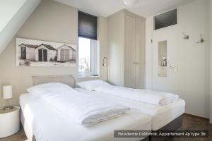 een witte slaapkamer met een groot bed met witte lakens bij Residentie Californië in De Koog