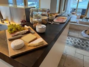 un mostrador con queso y otros alimentos en una tabla de cortar en Villa Fleurettes STUDIO en Le Châble