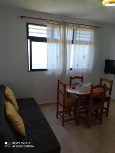 d'un salon avec une table, des chaises et une fenêtre. dans l'établissement Casa rural con Wifi, terraza y vistas al mar el La Palma, à Puntallana