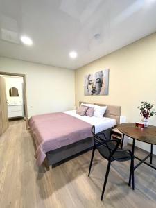 a bedroom with a large bed and a table at Alanta Apartments Easy Kaunas in Kaunas