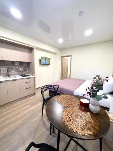 a bedroom with a bed and a table and a kitchen at Alanta Apartments Easy Kaunas in Kaunas
