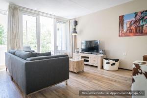 a living room with a couch and a tv at Residentie Californië in De Koog