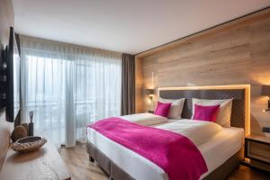 een slaapkamer met een groot bed en een roze deken bij Hotel Adapura Wagrain in Wagrain