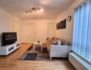 a living room with a couch and a tv at Demims Apartments Lillestrøm - Central location & Parking in Lillestrøm
