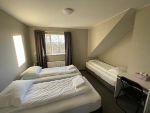 a room with two beds and a desk and a window at Guesthouse Bitra B&B in Selfoss