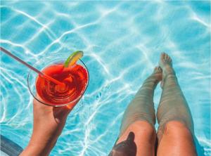 una persona sosteniendo una bebida en una piscina en Calipso Ocean Lodge, en Playa Avellana