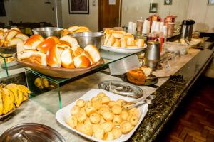 a buffet line with plates of bread and other foods at Amazonas Palace Hotel Belo Horizonte - By UP Hotel - Avenida Amazonas in Belo Horizonte
