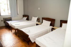 una camera con tre letti con lenzuola bianche di Amazonas Palace Hotel Belo Horizonte - By UP Hotel - Avenida Amazonas a Belo Horizonte