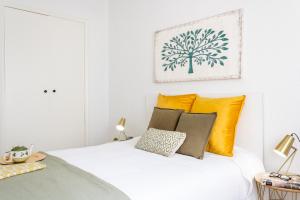 biała sypialnia z białym łóżkiem z żółtymi poduszkami w obiekcie Avda Pamplona Hospitales Universidad w mieście Barañáin