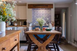 a kitchen with a wooden table with chairs around it at Thatched Hat Cottage in Lymington