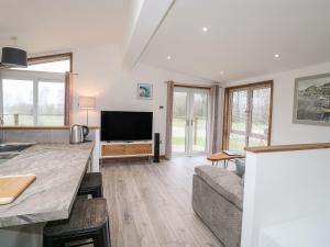 a kitchen and living room with a couch and a tv at 2 Meadow Retreat in Liskeard