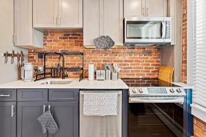 a kitchen with white cabinets and a brick wall at Urban Chic 1BR - Walk to Boardwalk - Min to Beach in Atlantic City