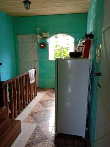um frigorífico num quarto com uma parede verde em Pousada Fonte Viva em Lavras Novas