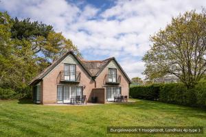 a large brick house with chairs in the yard at Bungalowpark 't Hoogelandt in De Koog