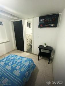 a bedroom with a bed and a table in it at Hospedaje Holcay in Bogotá