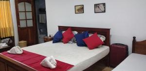 a bedroom with a bed with red and blue pillows at Kuma Beach side Villa in Wadduwa