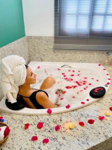 a woman sitting in a bath tub covered in roses at Pousada Casamar in Porto De Galinhas