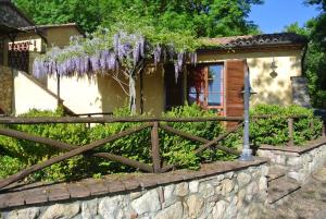 une clôture devant une maison avec des glycines violets dans l'établissement Borgo di Monte Murlo, à Guardistallo