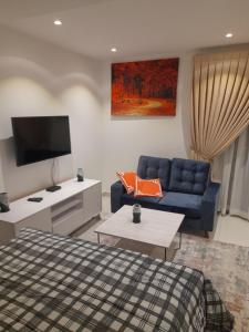 a living room with a bed and a blue couch at The Lennox D-Plus Apartments in Accra