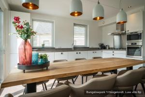 a kitchen with a wooden table with a vase of flowers at Bungalowpark 't Hoogelandt in De Koog