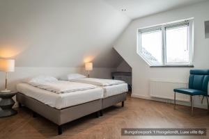 a bedroom with two beds and a blue chair at Bungalowpark 't Hoogelandt in De Koog