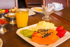 a plate of fruit on a table with a glass of orange juice at Hotel Verde Plaza in Santana do Livramento