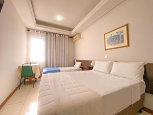 a bedroom with a large white bed in a room at Hotel Verde Plaza in Santana do Livramento