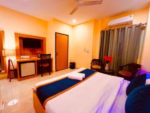 a bedroom with a bed and a desk and a television at Reo Resort, near bus stand & railway station ,Haridwar in Haridwār
