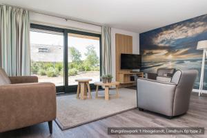 a living room with a couch and a tv at Bungalowpark 't Hoogelandt in De Koog