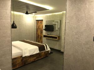 a bedroom with a bed and a tv on a wall at Aariv Inn BAGA BEACH in Baga