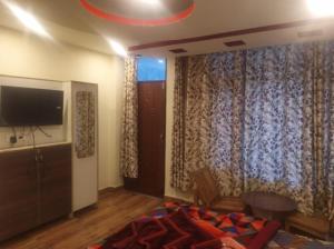 a bedroom with a bed and a tv and curtains at Him Taj by StayApart in Manāli