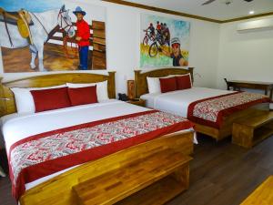 ein Schlafzimmer mit 2 Betten und einem Wandgemälde in der Unterkunft Hacienda Guachipelin Volcano Ranch Hotel & Hot Springs in Liberia