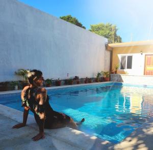 una mujer sentada junto a una piscina en Casa Terracota en Bacalar