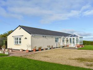 a white house with a patio and a yard at The Old Byre in Haswell