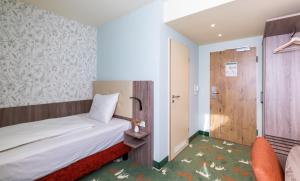 Hotel & Restaurant Hubertus Sehnde في سيهندي: غرفة صغيرة بها سرير وكرسي