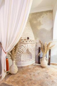 Habitación con chimenea de ladrillo y 2 jarrones en Riad Dar Elma And Spa, en Marrakech