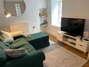 un soggiorno con divano verde e TV a schermo piatto di Gwandalan - 1 Bed Apartment, Within Tenby Town Walls a Tenby