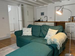 a living room with a green couch and a lamp at Gwandalan - 1 Bed Apartment, Within Tenby Town Walls in Tenby