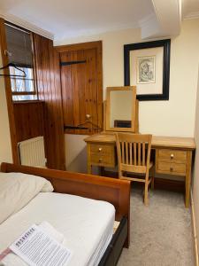 een slaapkamer met een bed, een bureau en een spiegel bij EdinB&B in Edinburgh