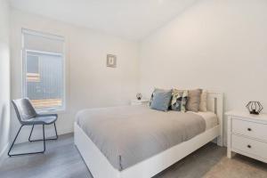 um quarto branco com uma cama e uma cadeira em Initial / Fika +spa / MSA em Saint-Férréol-les-Neiges