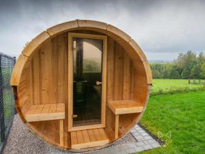 ein rundes Holzgebäude mit einer Tür auf einem Feld in der Unterkunft Tiny Fox Kluisbos in Orlitain