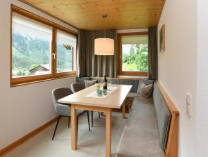 ein Esszimmer mit einem Tisch, Stühlen und Fenstern in der Unterkunft Ferienwohnungen Lingg in Schoppernau